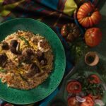 Margilan Plov on a green plate beside fresh produce.