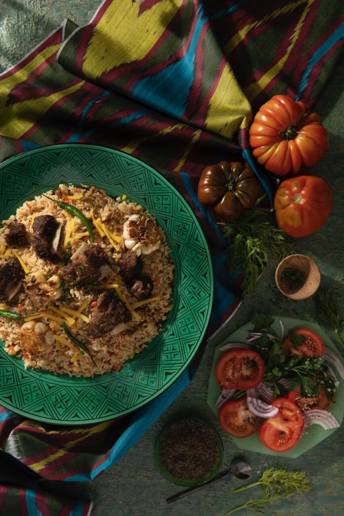 Margilan Plov Margilan Plov on a green plate beside fresh produce.