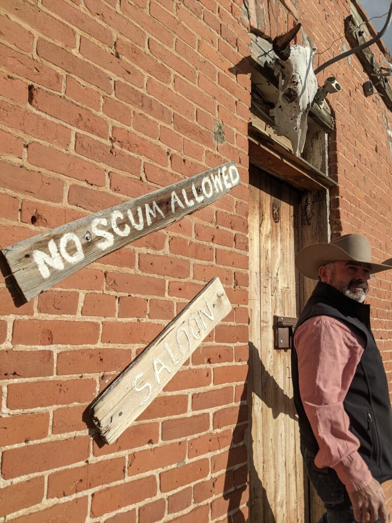 Outside of saloon with deer fixture and man in cowboy hat