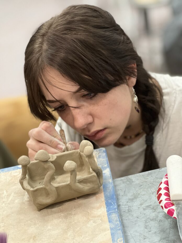 Tumbleroot 1 girl looking closely at sculpture on table