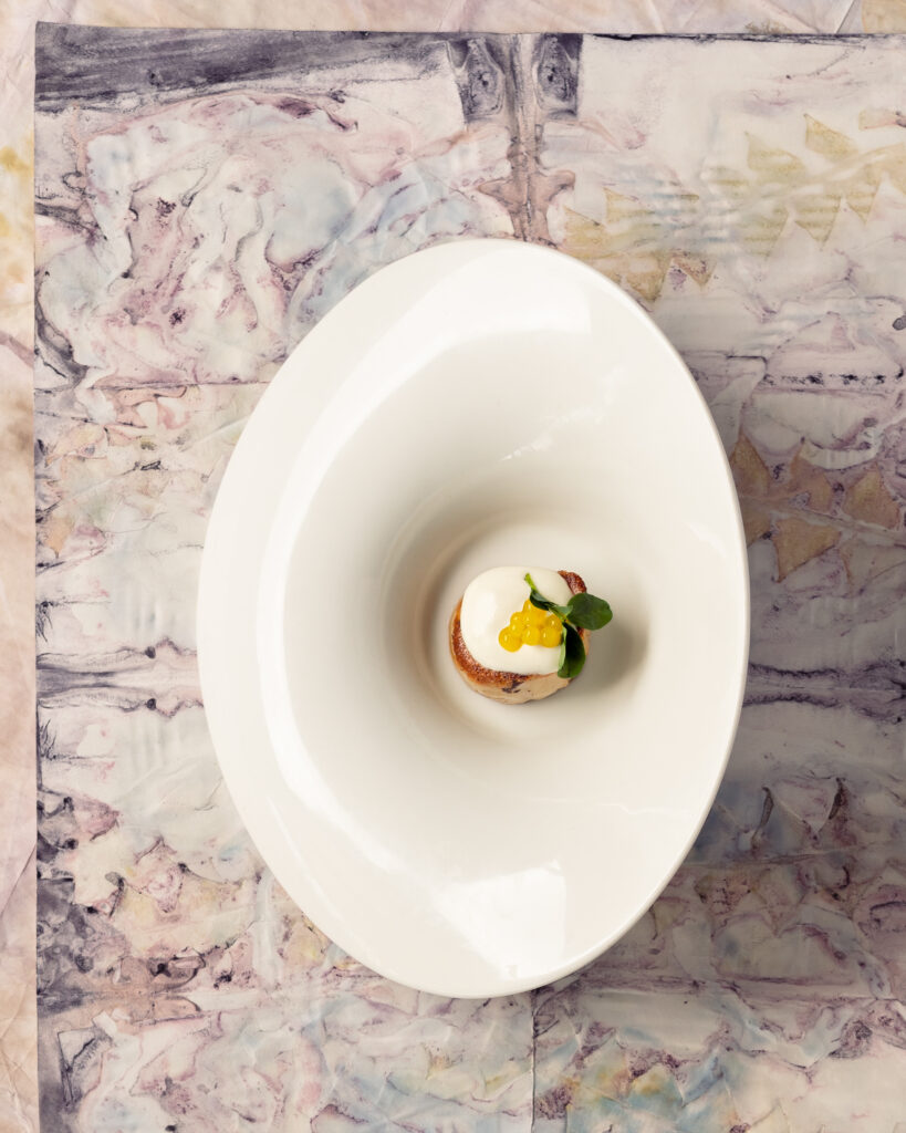 A small appetizer from Scalo on a white platter and white marble table. 