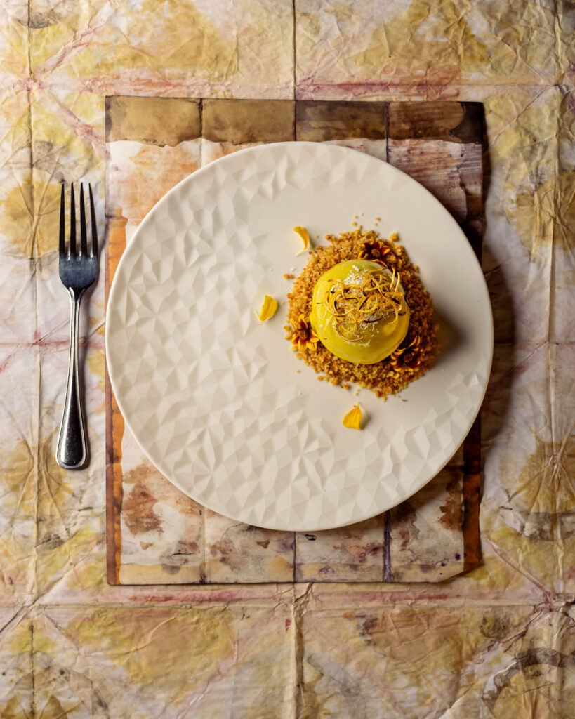 A yellow appetizer on a white plate on a yellow place setting at Scalo. 