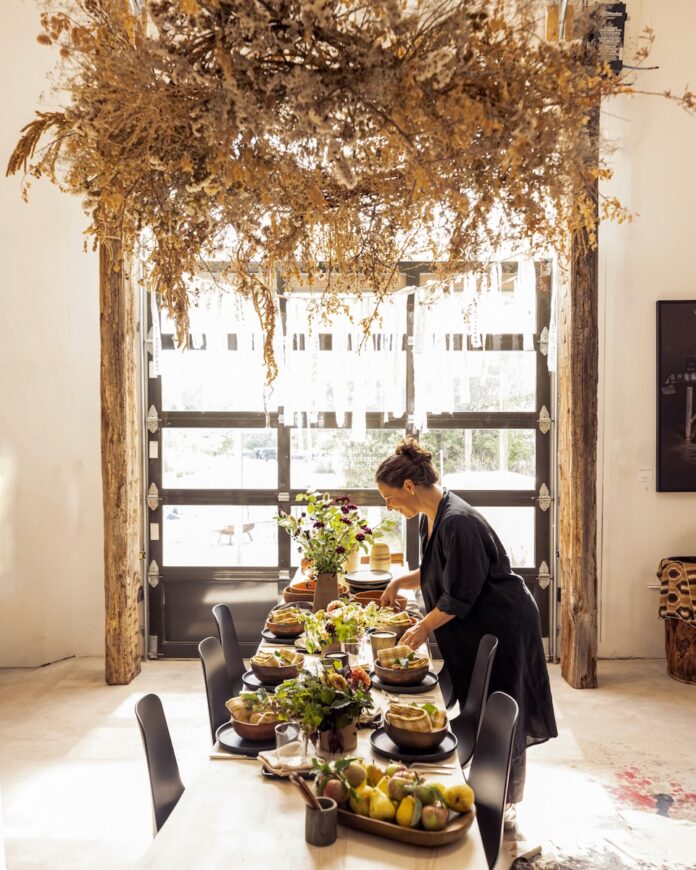 Woman in black sweater setting up a table in living Threads