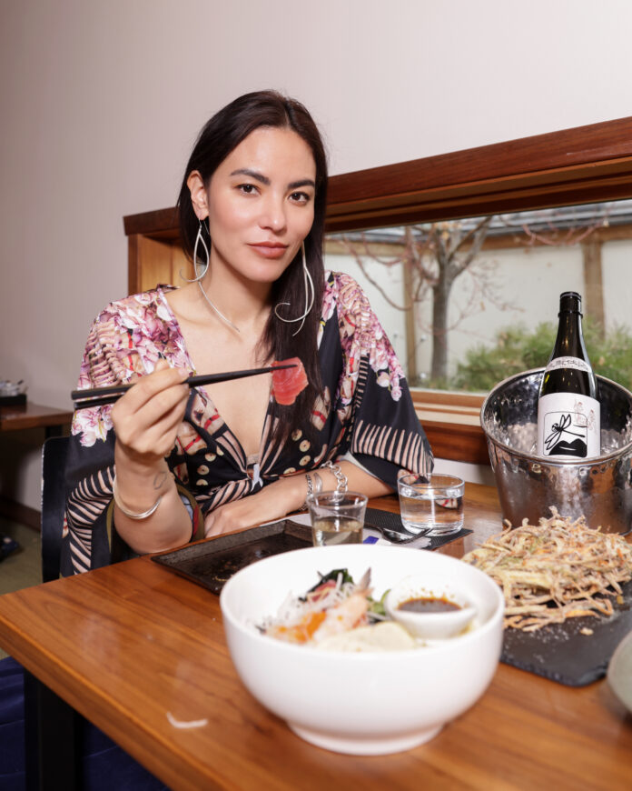 A woman picks up a piece of salmon with chopsticks.