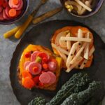 Vegetable Escabeche on toast on a black plate.