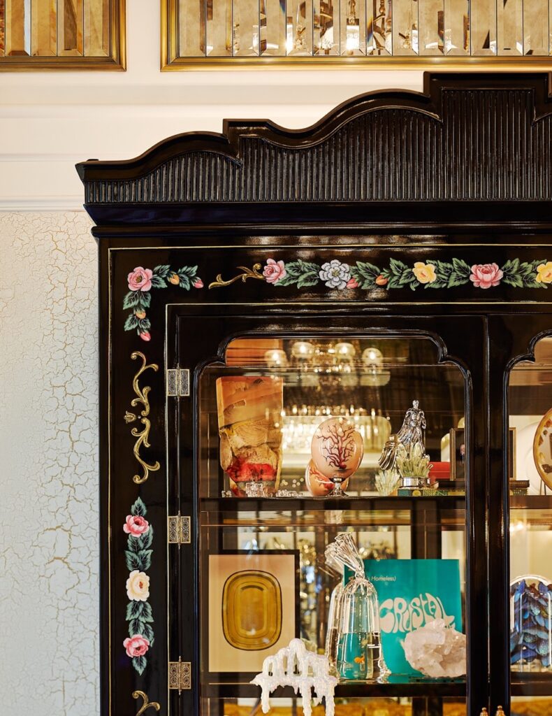A china cabinet corner with antiques inside.