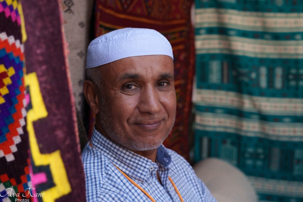 International Folk Art Market 2025 TABLE Magazine 3 A man stands amongst a display of rugs