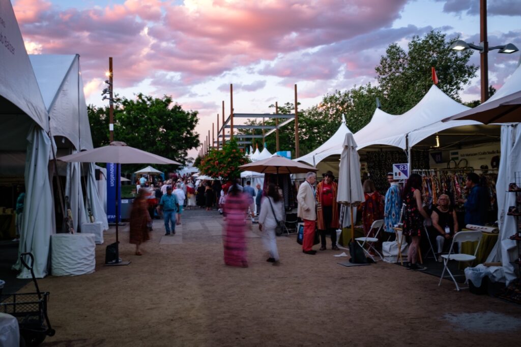International Folk Art Market 2025 TABLE Magazine 6 People walk down an aisle of artist tents.