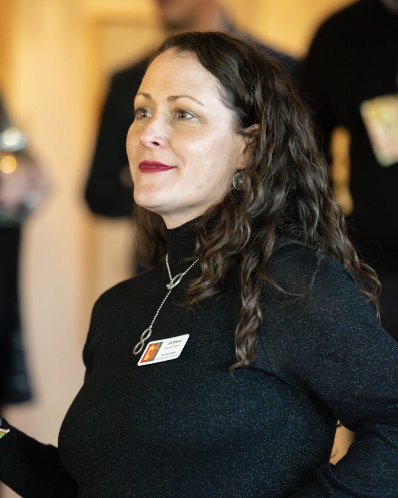 A woman of a nonprofit with a black turtleneck and name tag.