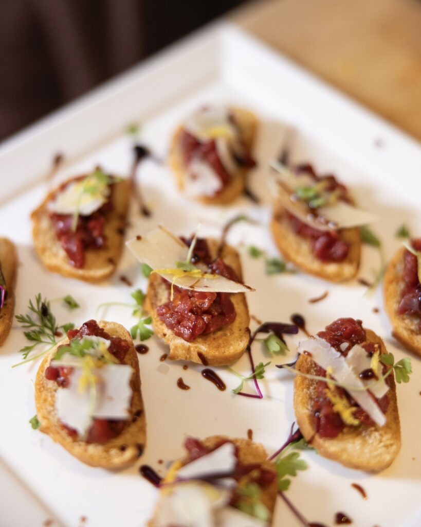 A Variety of small toasts with cheese and meat on top.