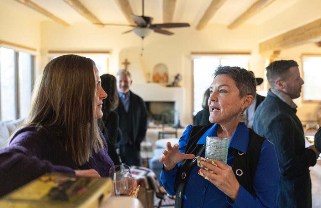 Two women from nonprofits in New Mexico talk in a dining area.