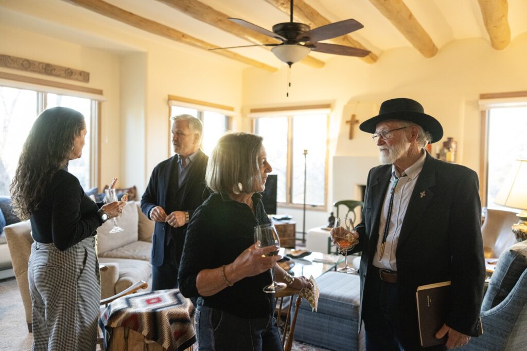 People with wine glasses from nonprofits talk in a tan room.