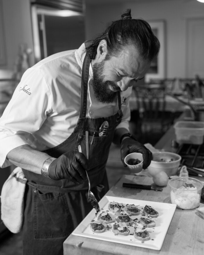A man laddling sauce onto appetizers.