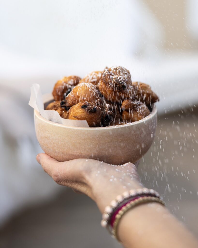 A fried dessert gets dusted with powdered sugar.
