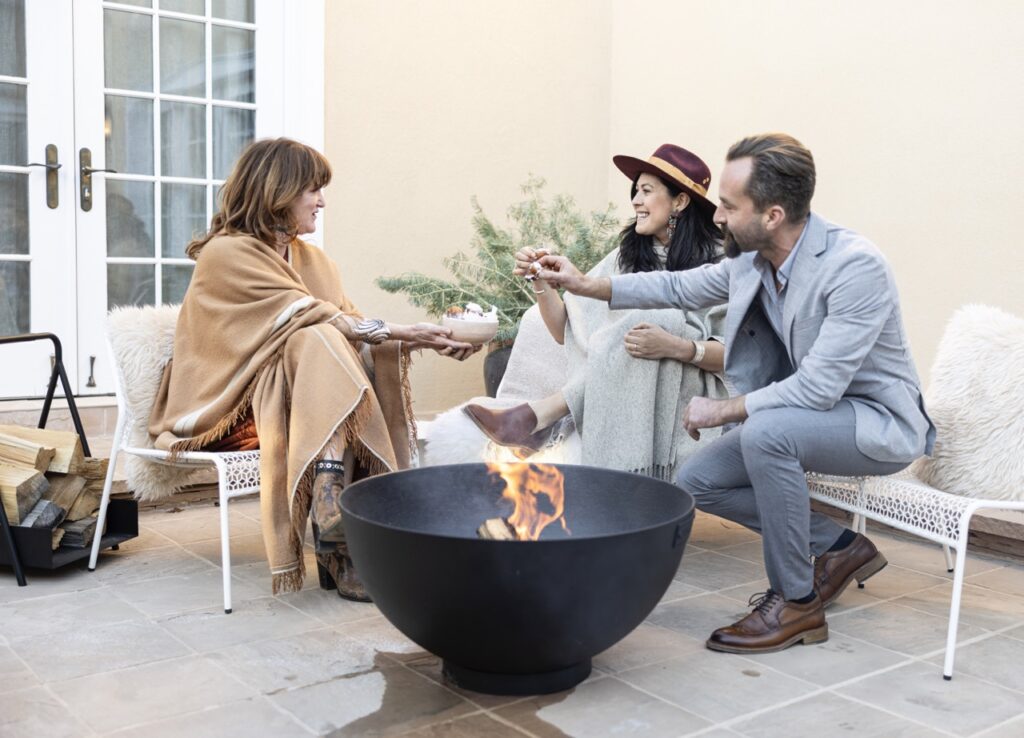 A group of people sit around a fire outside.