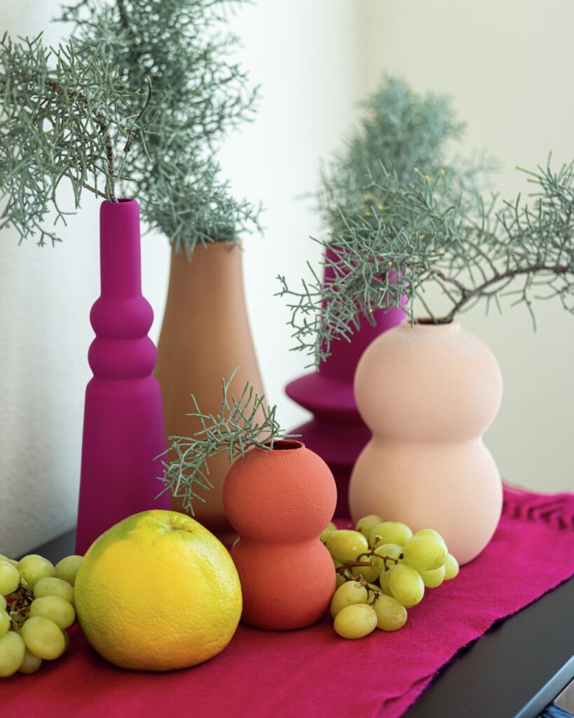 Various pink, purple, and orange vases on a table.