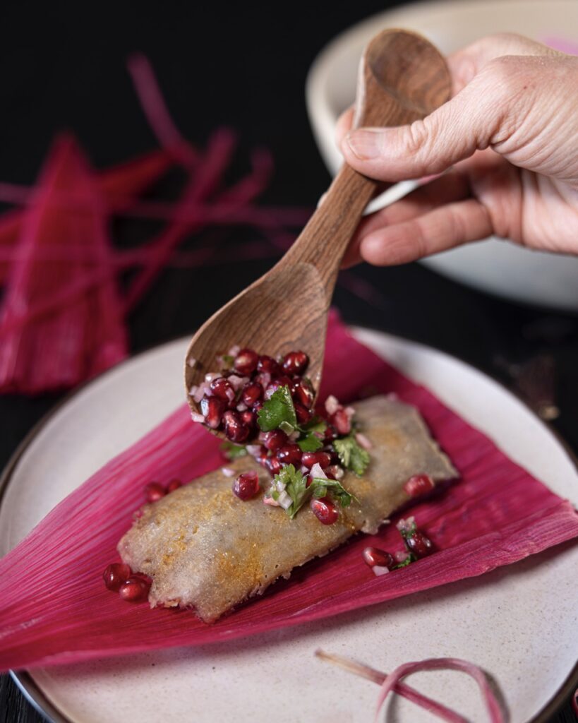 A purple husk with a pomegranate filling being sprinkled over top.