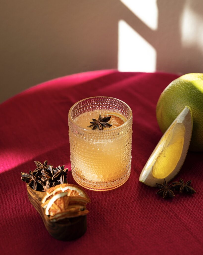 A short glass of an orange drink with a star anise floating inside.