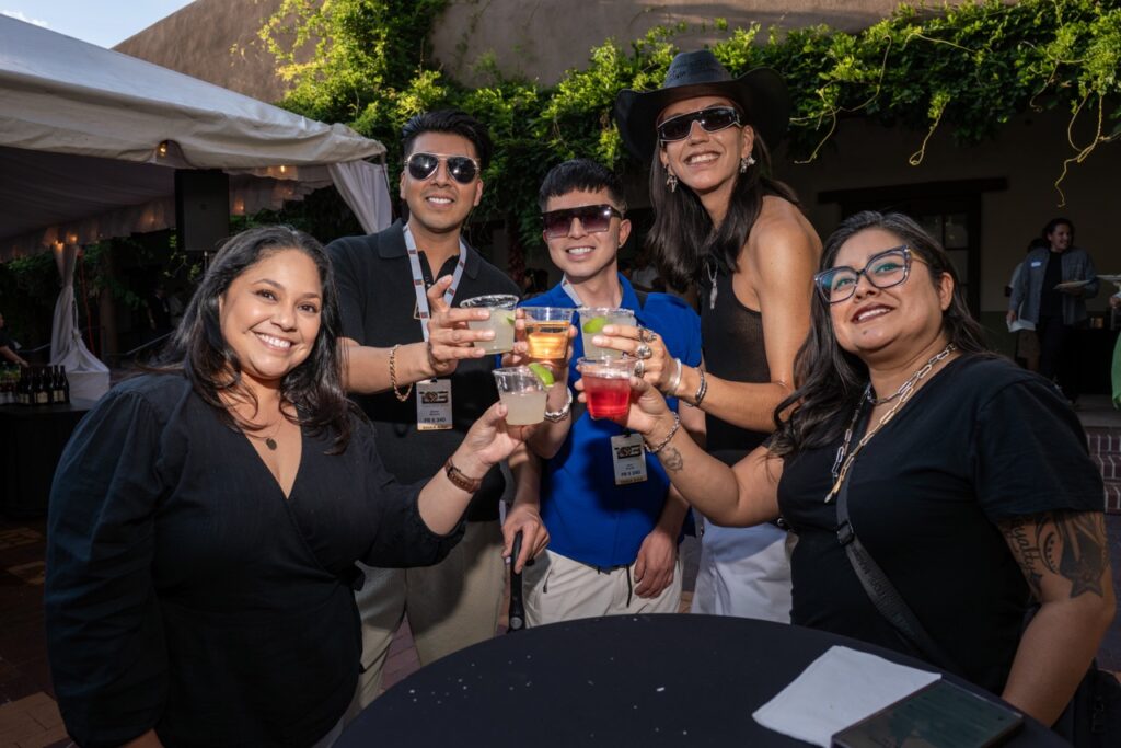 Santa Fe Indian Market 2025 Recap TABLE Magazine 2 A group of friends cheers plastic cocktail cups at a table.