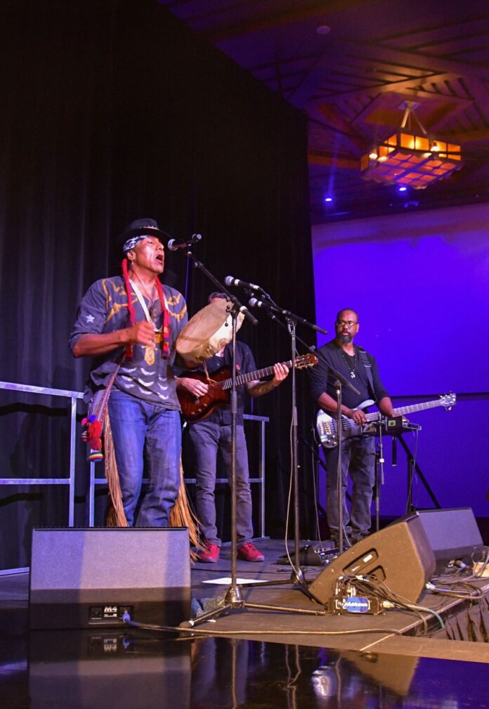 Three native men perform on stage.