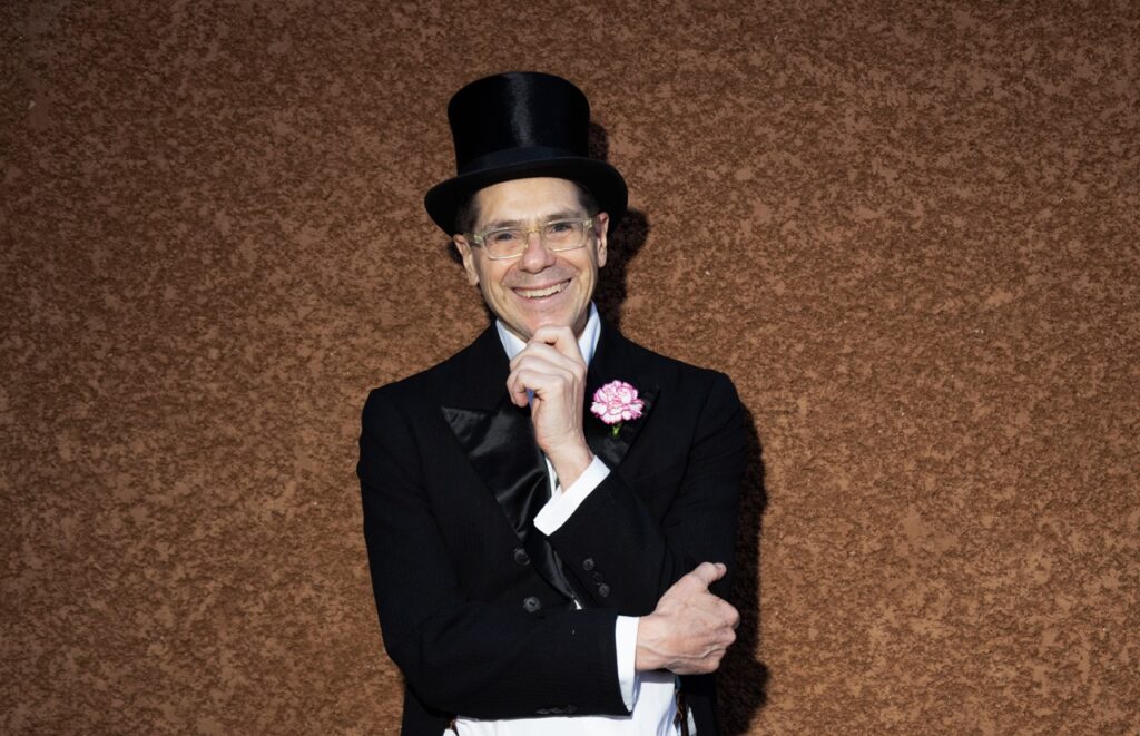 Audience Expeirence Portrait Series June 27 2025 Santa Fe Opera A man in a top hat and suit jacket with a pink flower in the lapel.