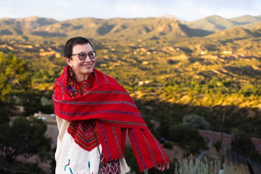 Santa Fe Opera Audience Portrait Series June 28 2025 A woman in a red pattern poncho in front of a mountain range.