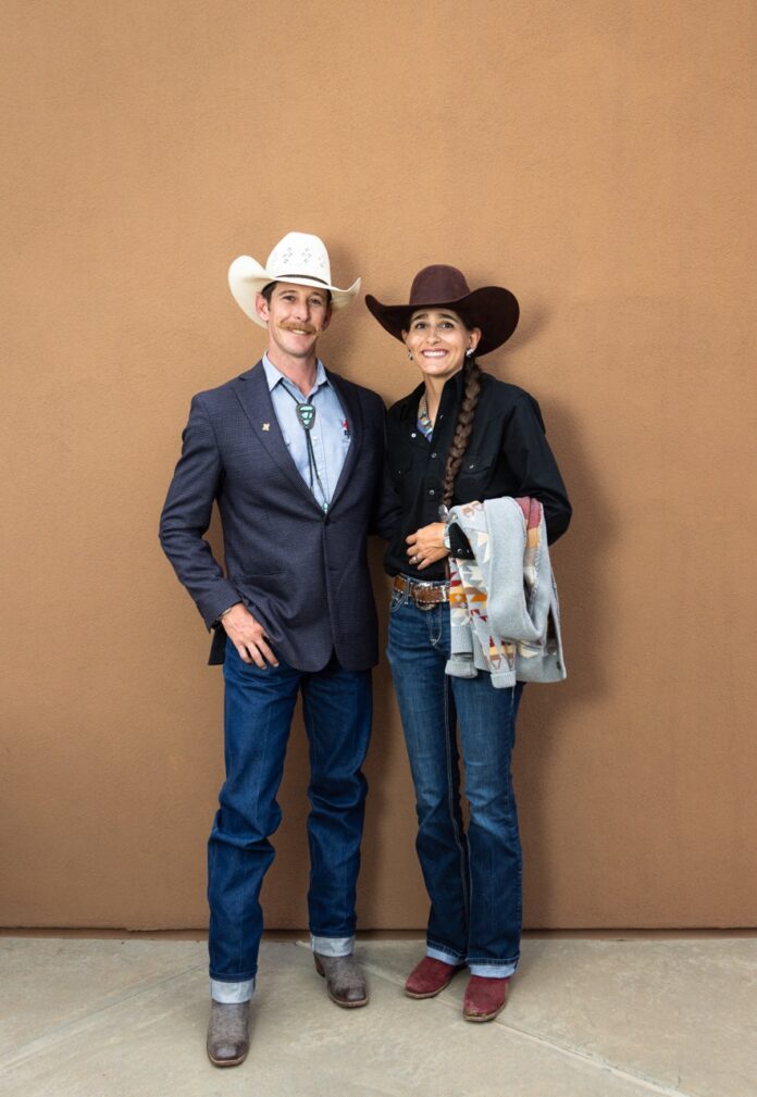 A man in a white cowboy hat and a woman in a brown cowboy hat stand together.
