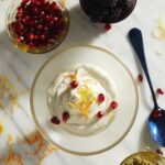 Sugar-Free Cashew Cream with lemon zest, pomegranate seeds, and fresh blackberries and raspberries on a marble counter.