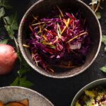 A bowl filled with vibrant purple and yellow julienned red cabbage, radicchio, and peppers, garnished with scallions.