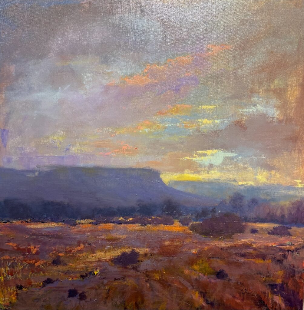 Oil painting 'Seeing Light' by Pamela Cuming, depicting a vast southwestern landscape with dark mesas, brush in the foreground, and a sky filled with dramatic pink and yellow sunset clouds.