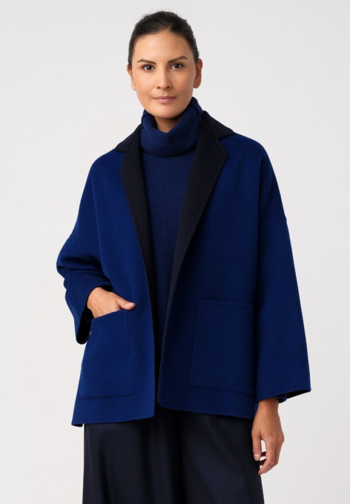 A woman models a reversible cobalt blue and black double-faced cashmere jacket by Italian designer Daniela Gregis over a turtleneck sweater.