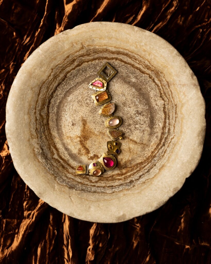 A sterling silver and 22K gold bracelet by Sydney Lynch with pink tourmaline, topaz, and rosy carnelian stones set in mismatched bezels.