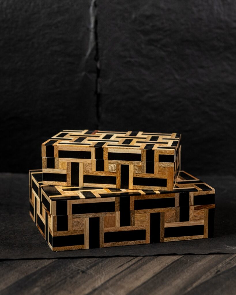 Two nesting decorative wooden boxes with a black and light wood geometric basket-weave pattern on a dark background.