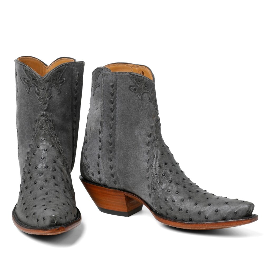 A pair of charcoal gray unisex Western boots made with prized ostrich leather on the toe and a stacked wooden heel.