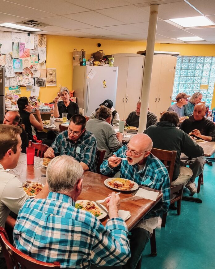 Groups of people sit at tables eating breakfast in a yellow room.