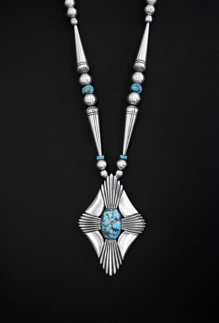 A silver and blue necklace lays on a black background.