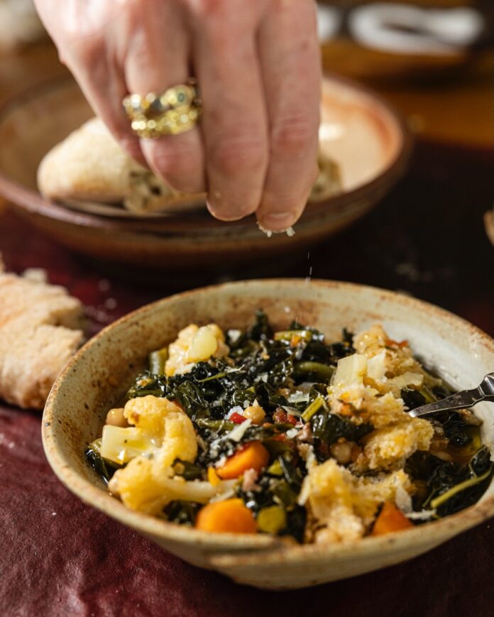 Hand drizzling cheese onto a dish