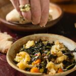 Hand drizzling cheese onto a dish