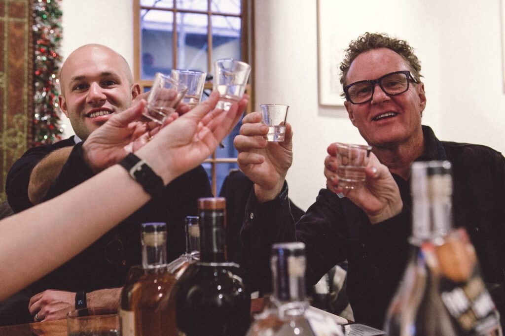 A group of people cheers drinks over a table.