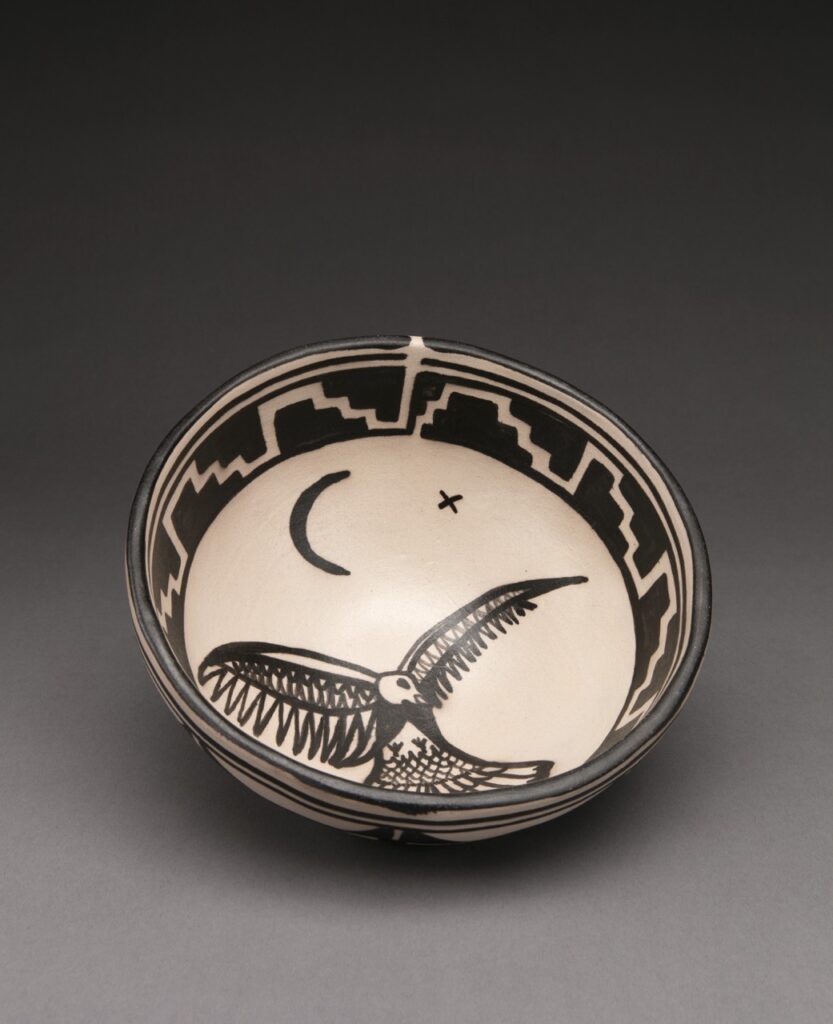 A handcrafted bowl in cream in black with a bird on it.