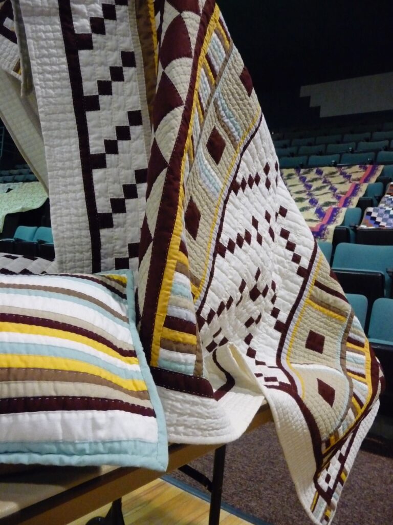 A red, white, and yellow quilt lays on a chair.