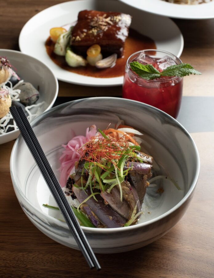 A plate of seafood with veggies on top with chopsticks on top of the plate.