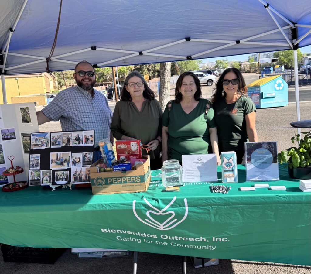 A group of three women and a man stand behind a green table.