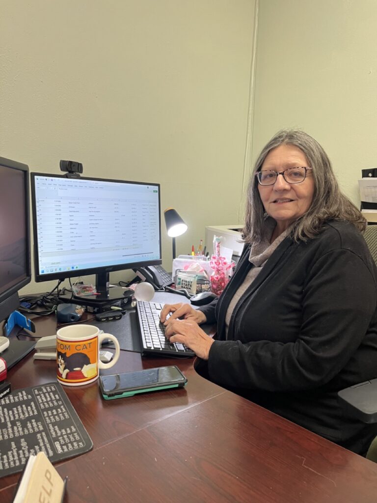 Susan Tarver sits at a desk on her computer.