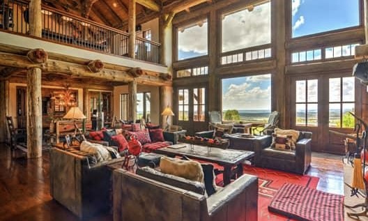 The 2 story interior living space of Blame Her Ranch with sprawling window views of the outdoors.