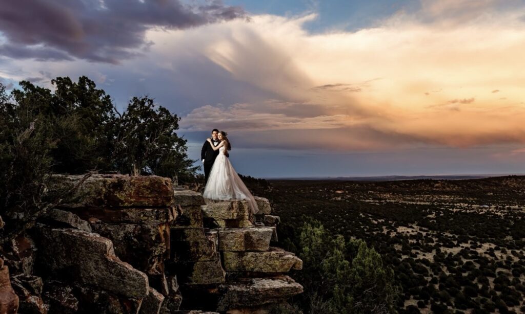 A married couple posing for a wedding photo standing atop a mesa near Blame Her Ranch.