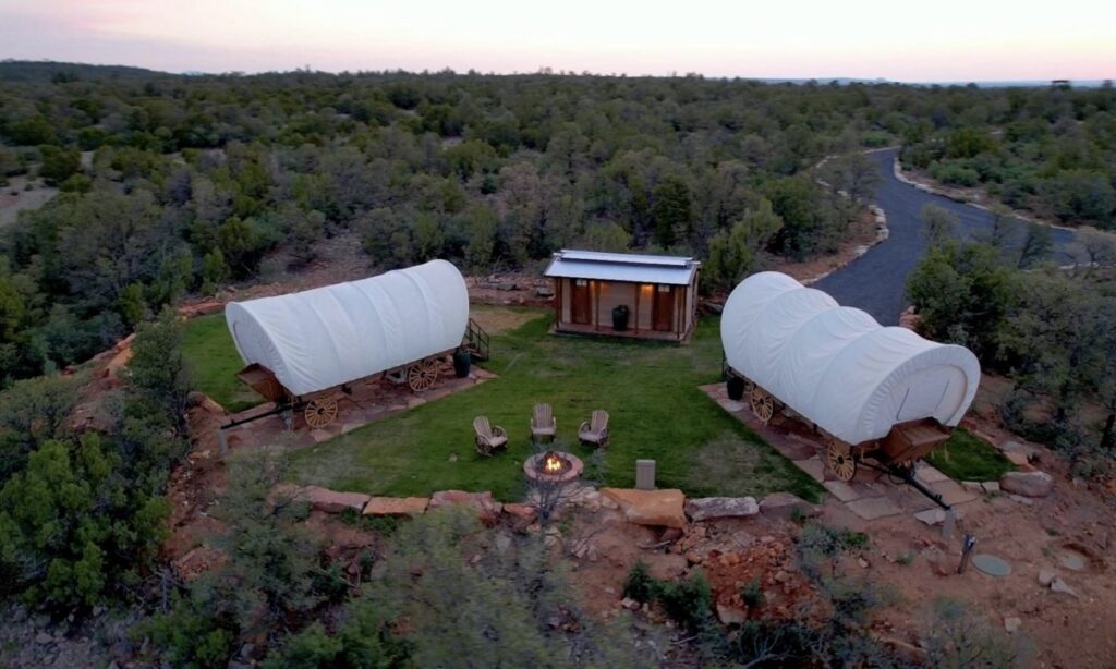 An arial view of ranch wagons in a mountain area with chairs and a fire pit between them.