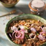 A bowl of Bolita Bean and Fennel Sausage Soup sits on a table.