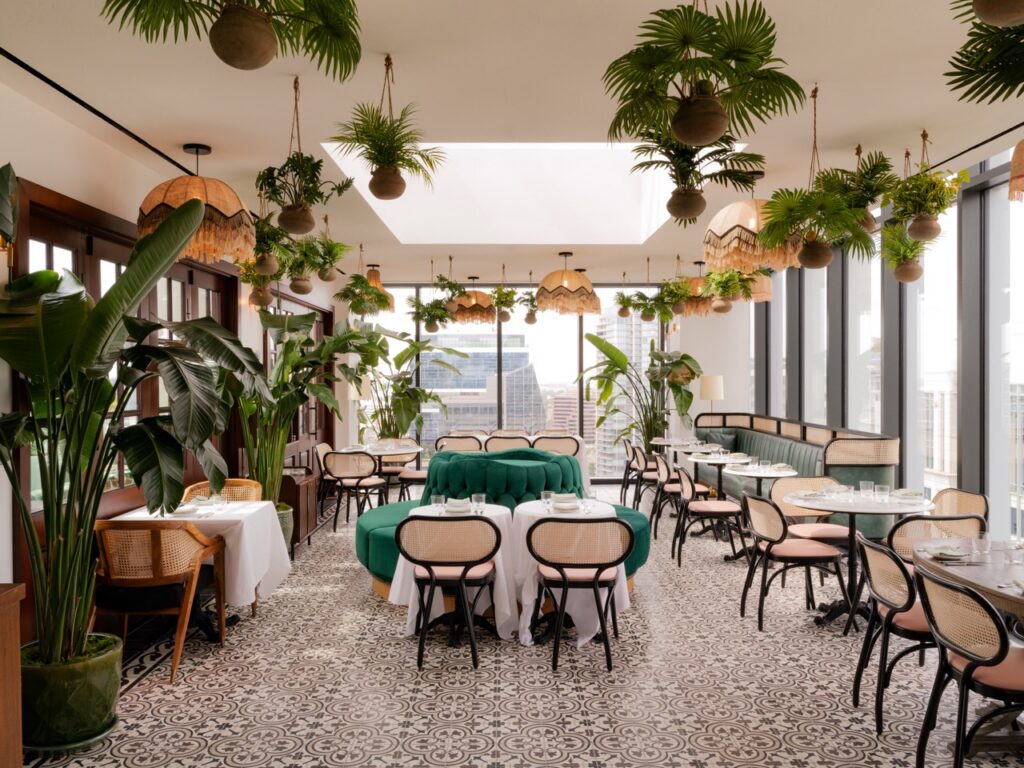 The inside of a dining area in sunshine with plants everywhere.