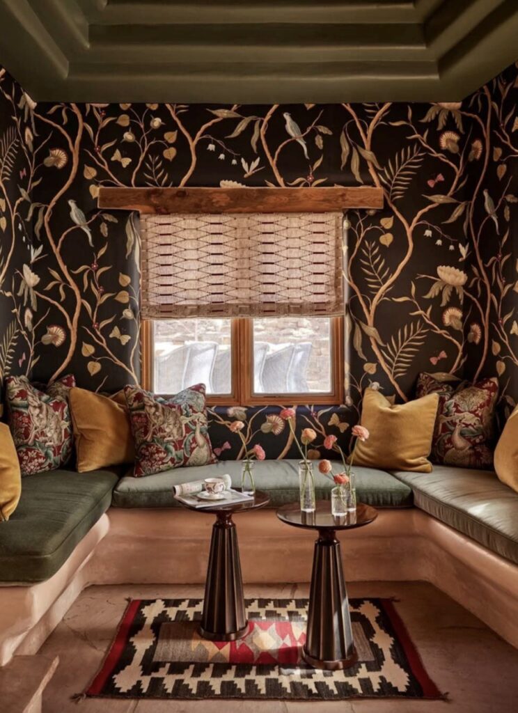 Floral vine wallpaper around a corner eating space with booths and small tables.